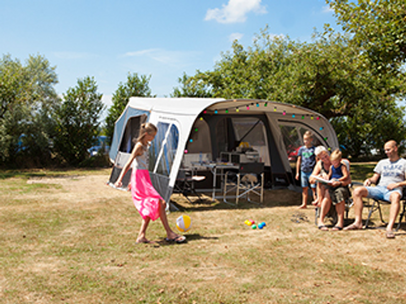 Familie voor tent met spelende kinderen